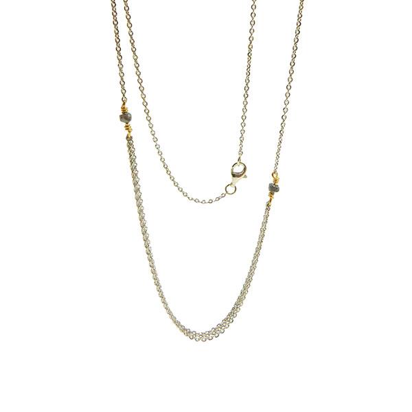 Elegant halskæde i sølv/guld med tre rækker og antracit diamanter, på hvid baggrund.